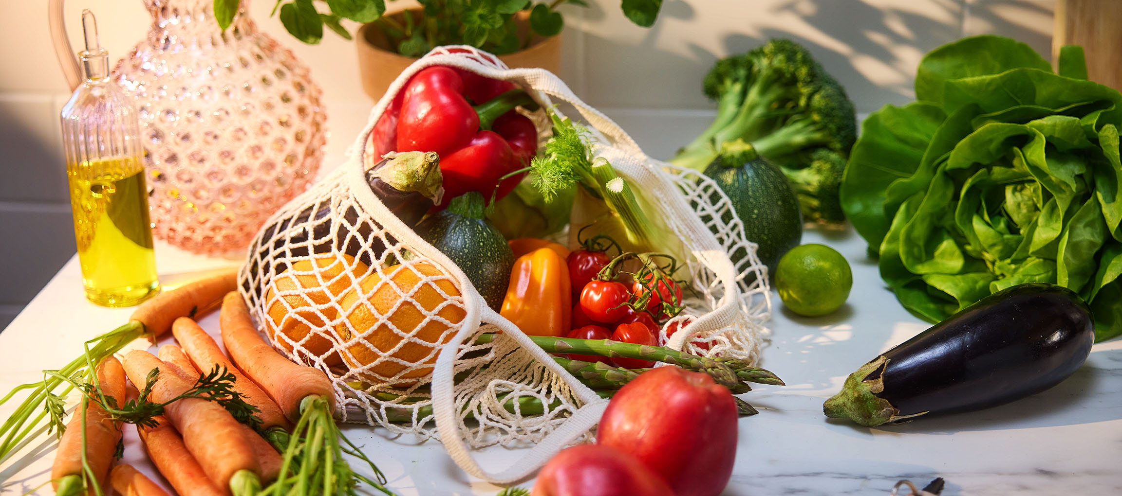 Légumes et fruits frais, dont carottes, poivrons, tomates, laitue et aubergine, sur une table.