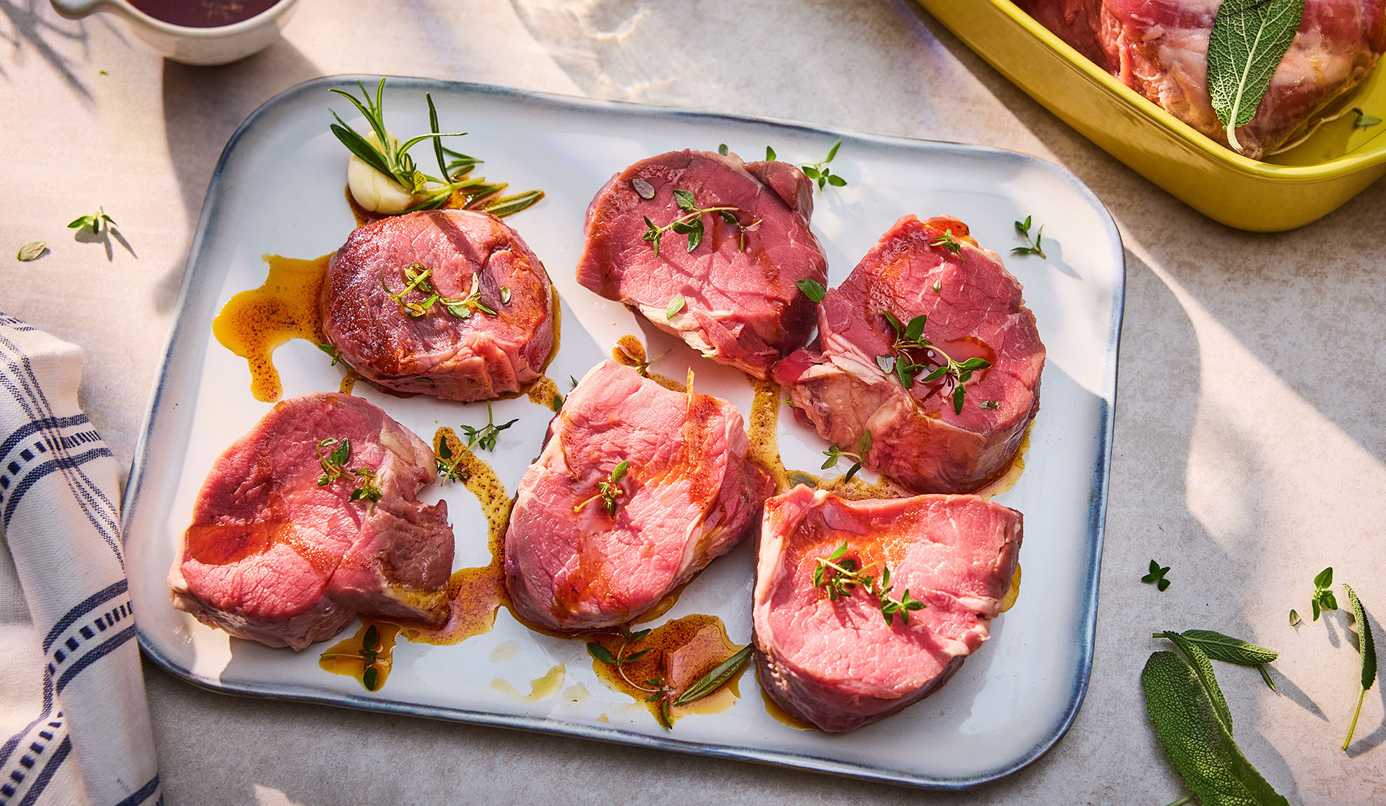 Médaillons de bœuf crus aux herbes et à l'huile sur un plat blanc