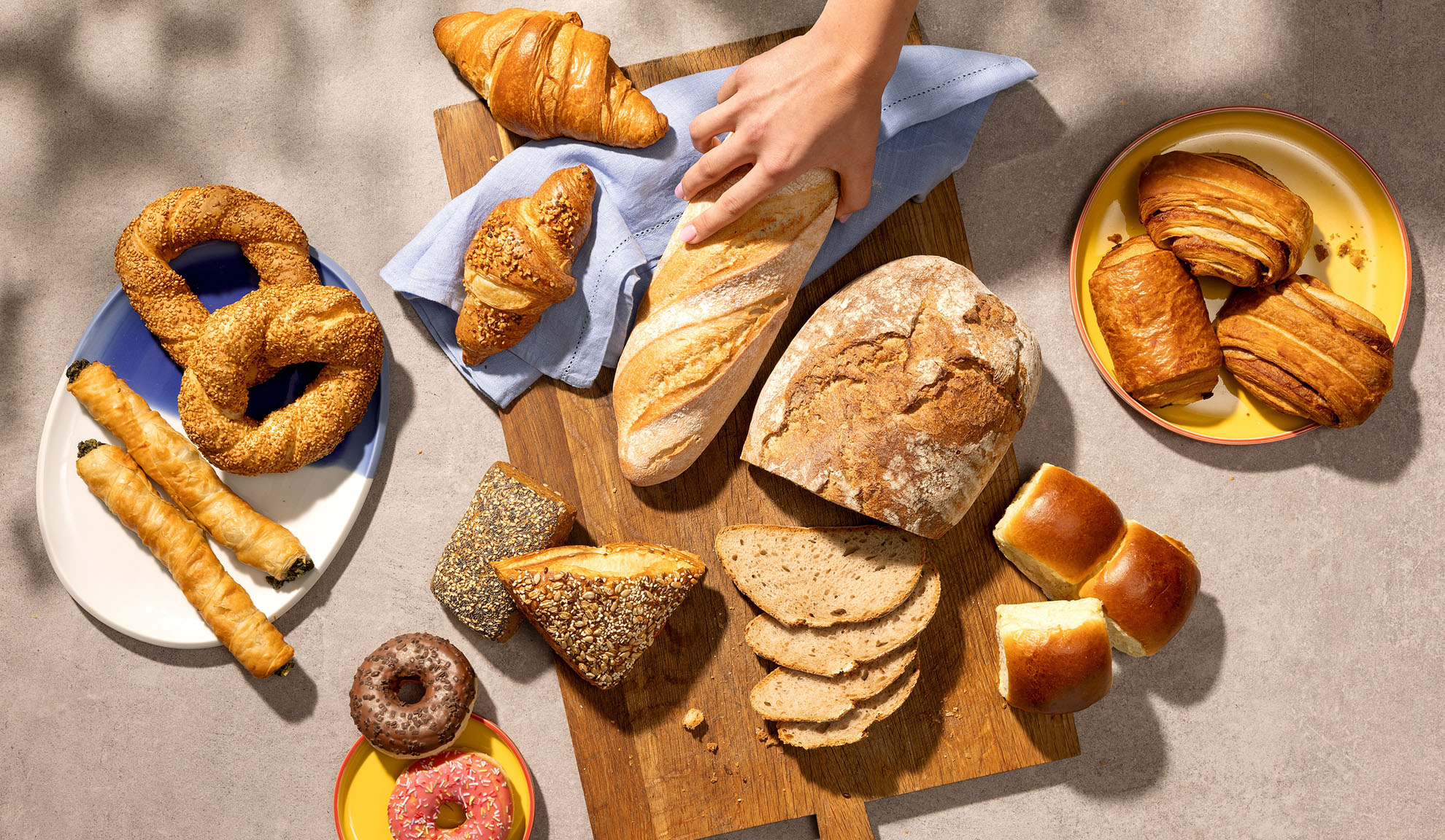 Assortiment de produits de boulangerie frais, y compris du pain, des croissants, des pâtisseries et des beignets sur une table.
