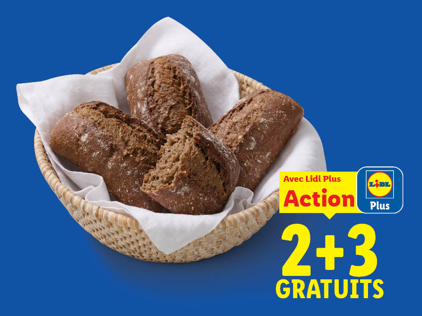 Cinq petits pains foncés dans une corbeille en osier avec un tissu blanc, accompagnés d'un macaron promotionnel Lidl Plus indiquant 'Action 2 + 3 GRATUITS'.