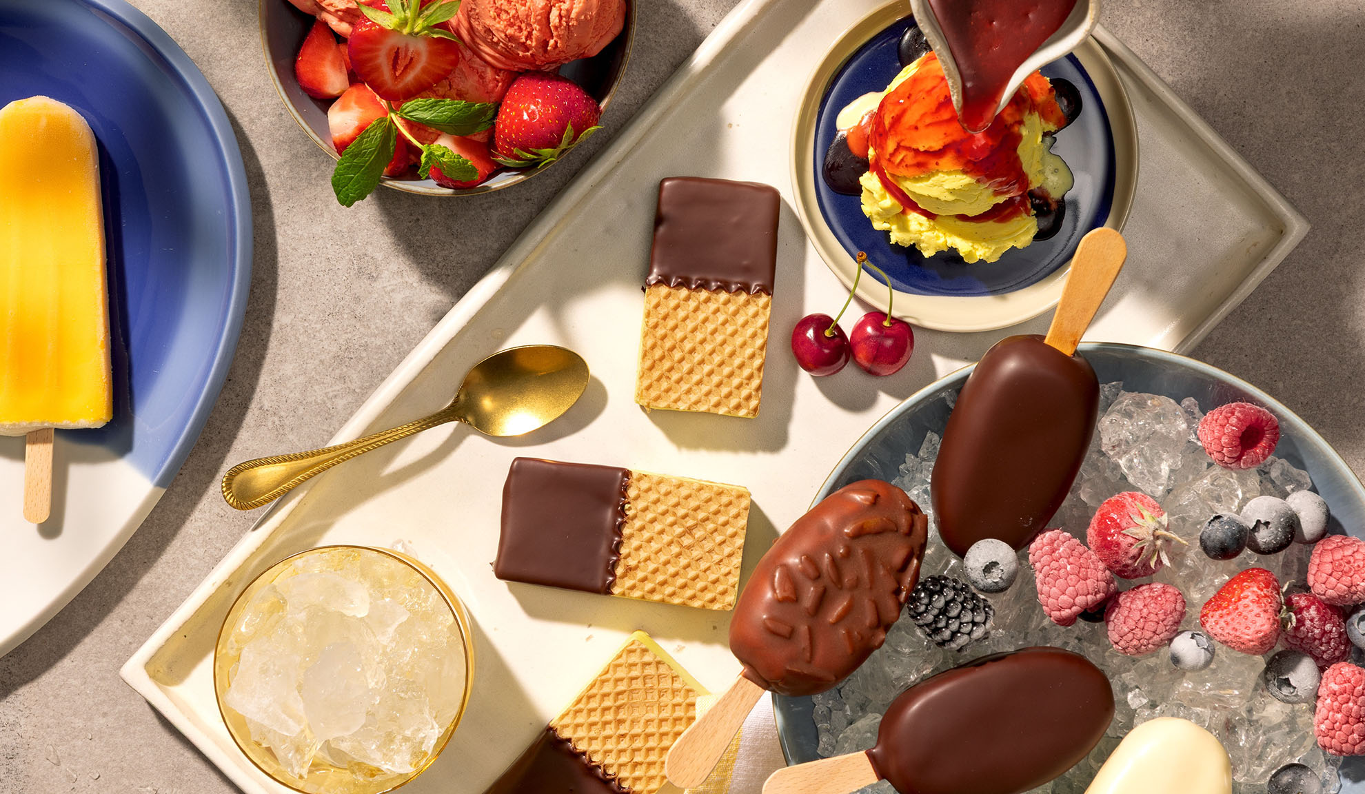 Assortiment de bâtonnets de glace, esquimaux, gaufres et baies sur un plateau.