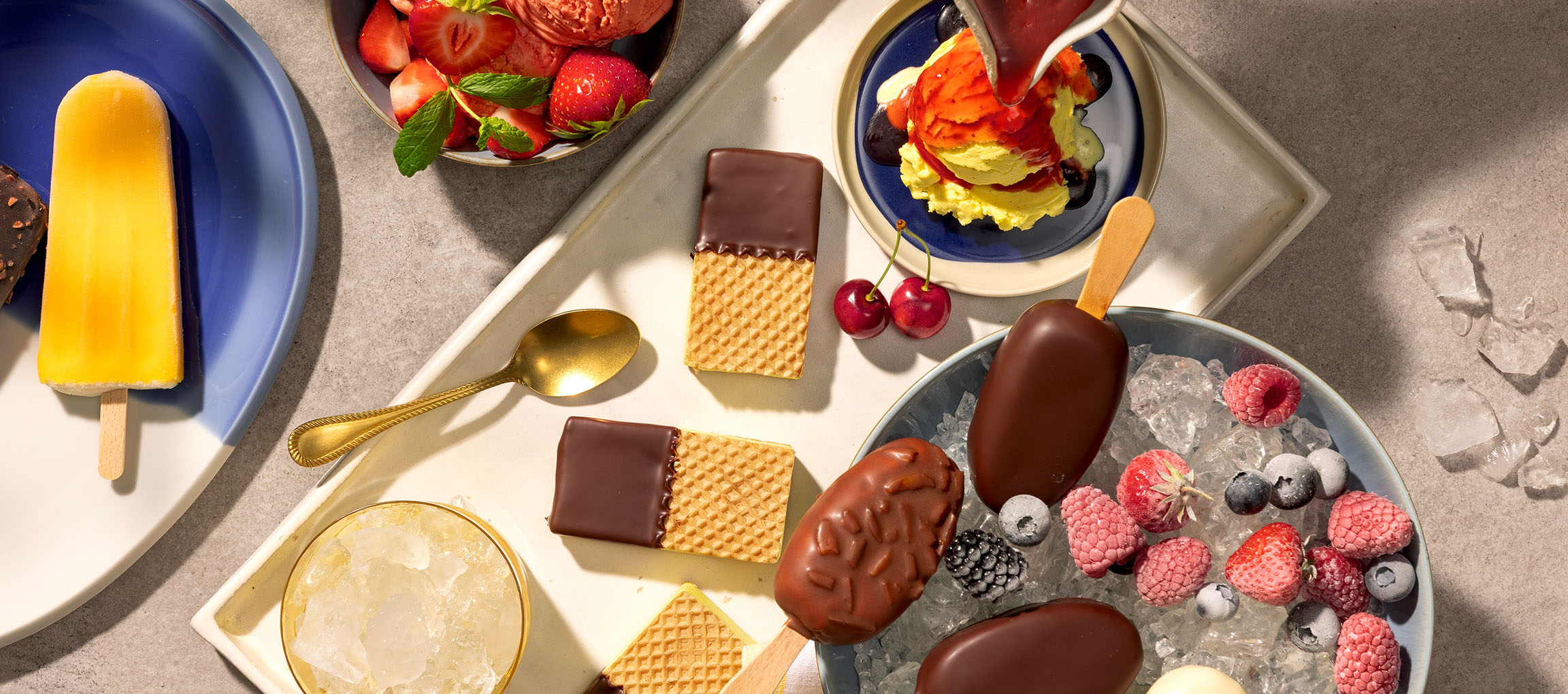 Assortiment de bâtonnets de glace, boules de glace et gaufrettes enrobées de chocolat avec des baies.