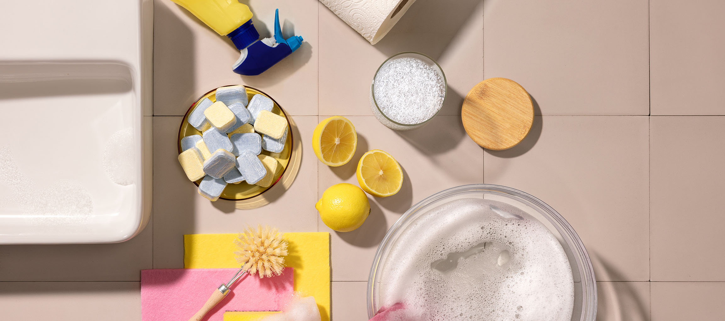 Produits de nettoyage: tablettes lave-vaisselle, citrons, vaporisateur, essuie-tout, brosse, éponges.