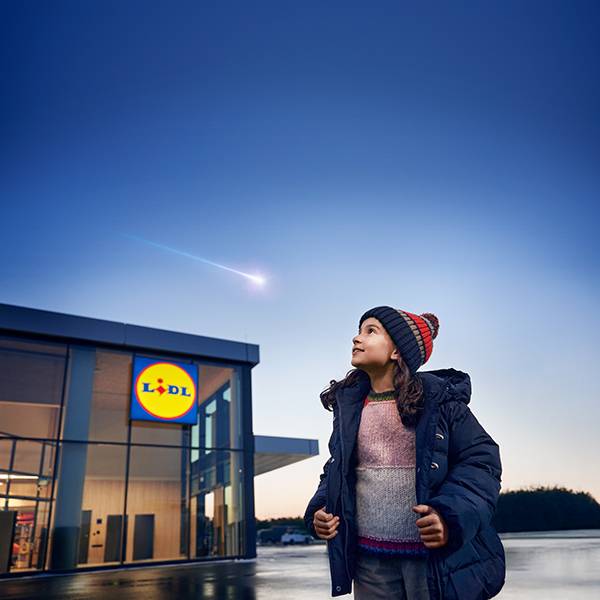 Une fille regarde une étoile filante au-dessus d'un magasin Lidl.