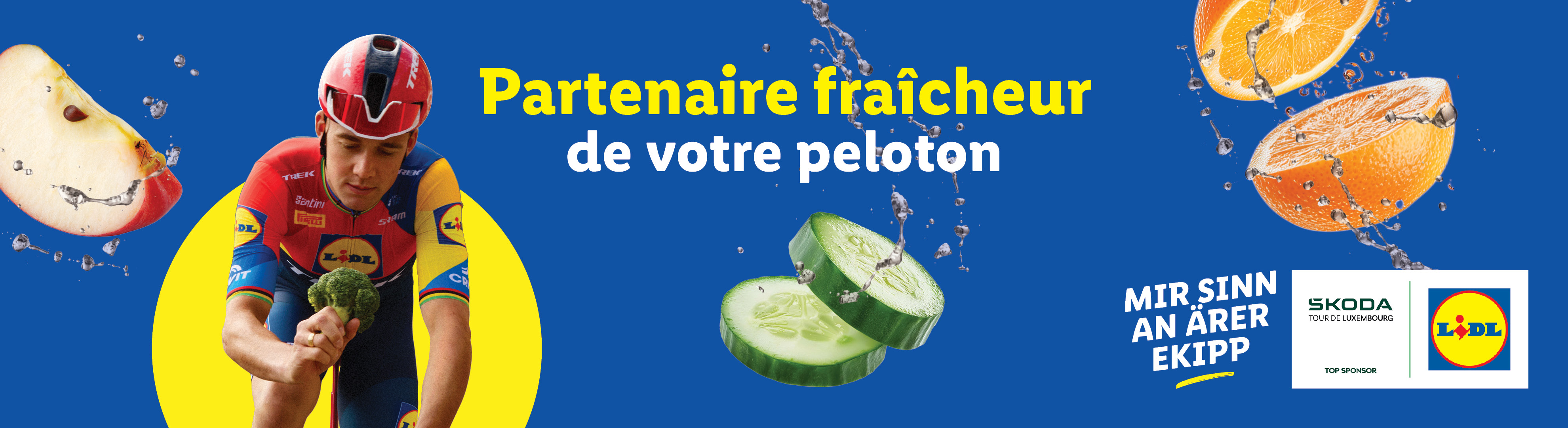 Un cycliste avec des fruits et légumes frais, dont une pomme, du concombre et des oranges, avec les logos Lidl et Skoda.