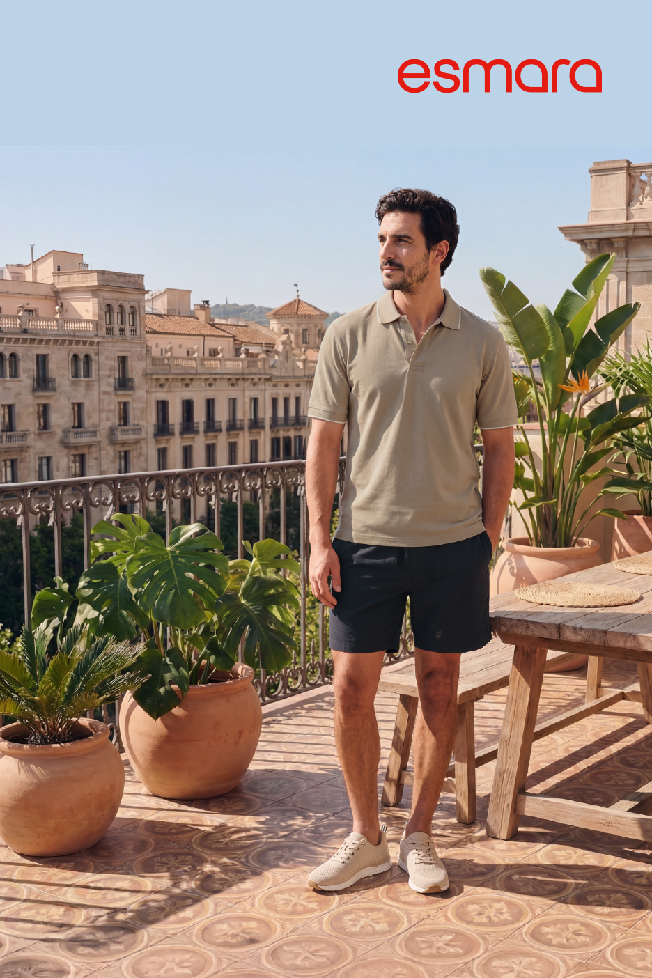 Un homme porte un polo et un short sur un balcon ensoleillé avec une vue sur la ville.