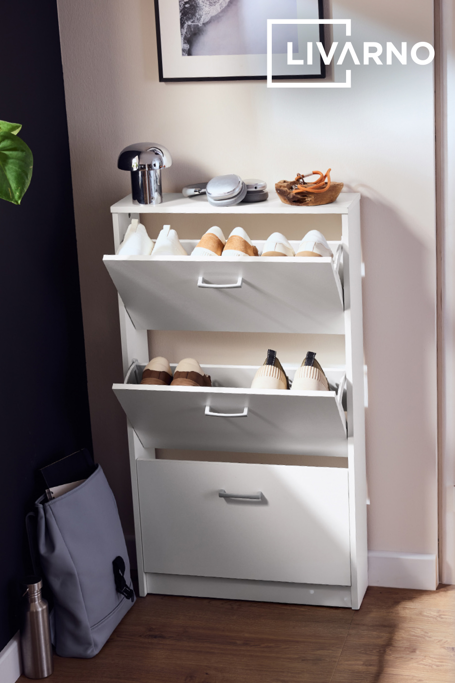 Meuble à chaussures blanc avec trois compartiments, rempli de chaussures et d'accessoires d'entrée.