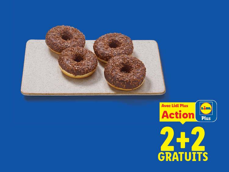 Quatre donuts au chocolat sur un plateau, avec une offre 2+2 gratuits.
