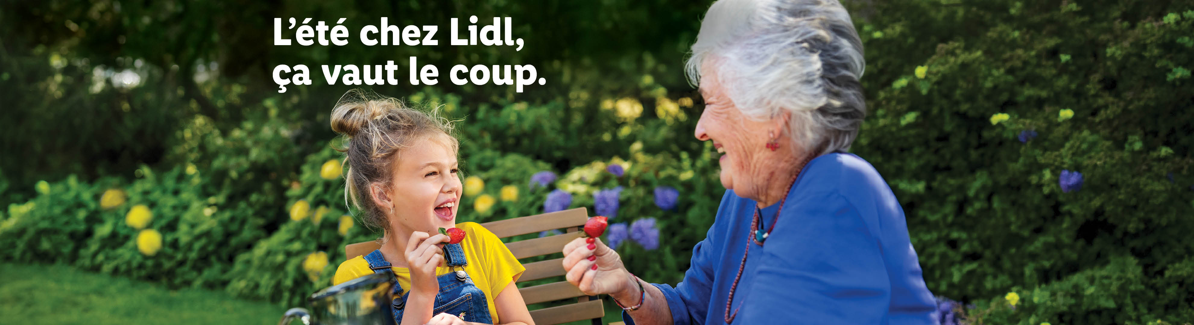 L'été chez Lidl, ça vaut le coup. Une grand-mère et sa petite-fille rient en mangeant des fraises.