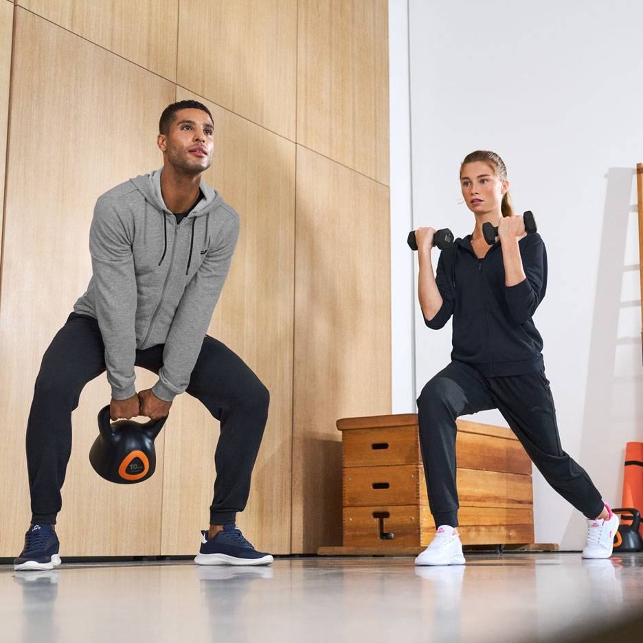 Homme et femme en tenue de sport, s'entraînant avec un kettlebell et des haltères.