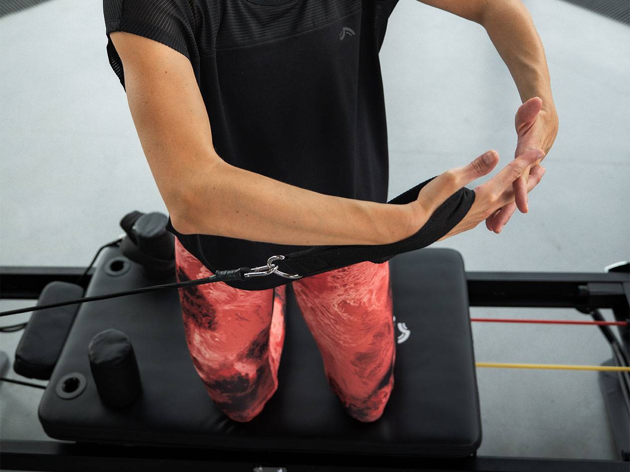 Femme s'entraînant avec des bandes de résistance sur un appareil de Pilates.