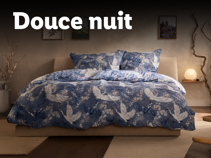 Literie bleue avec motif de grues et papillons dans une chambre à coucher.