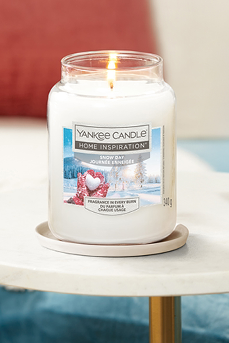 Une bougie Yankee Candle Home Inspiration 'Snow Day' allumée sur une table.