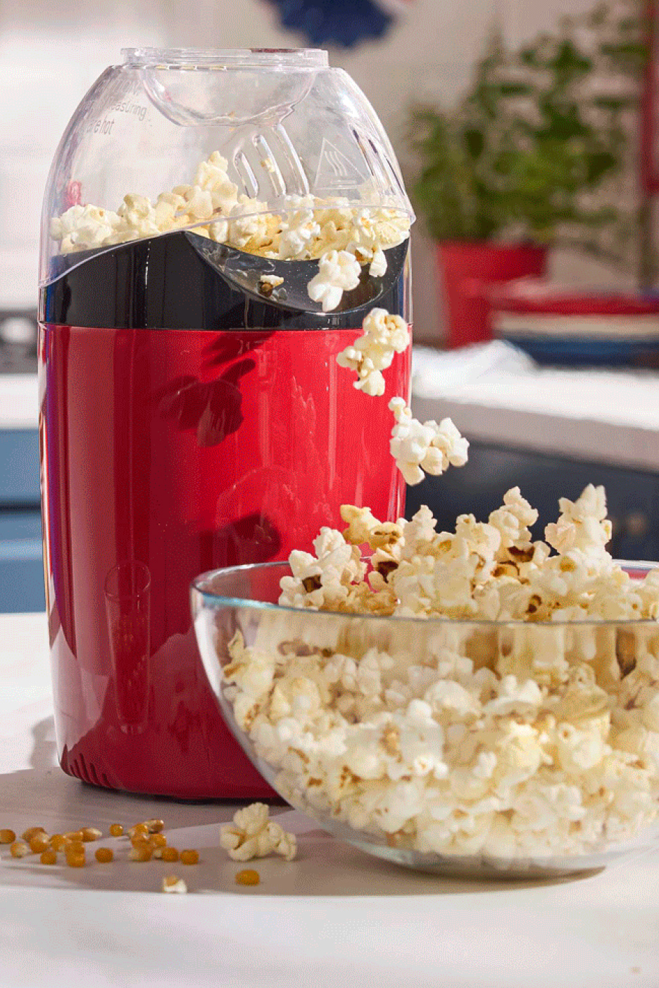 Machine à popcorn rouge remplissant un grand bol de popcorn frais.