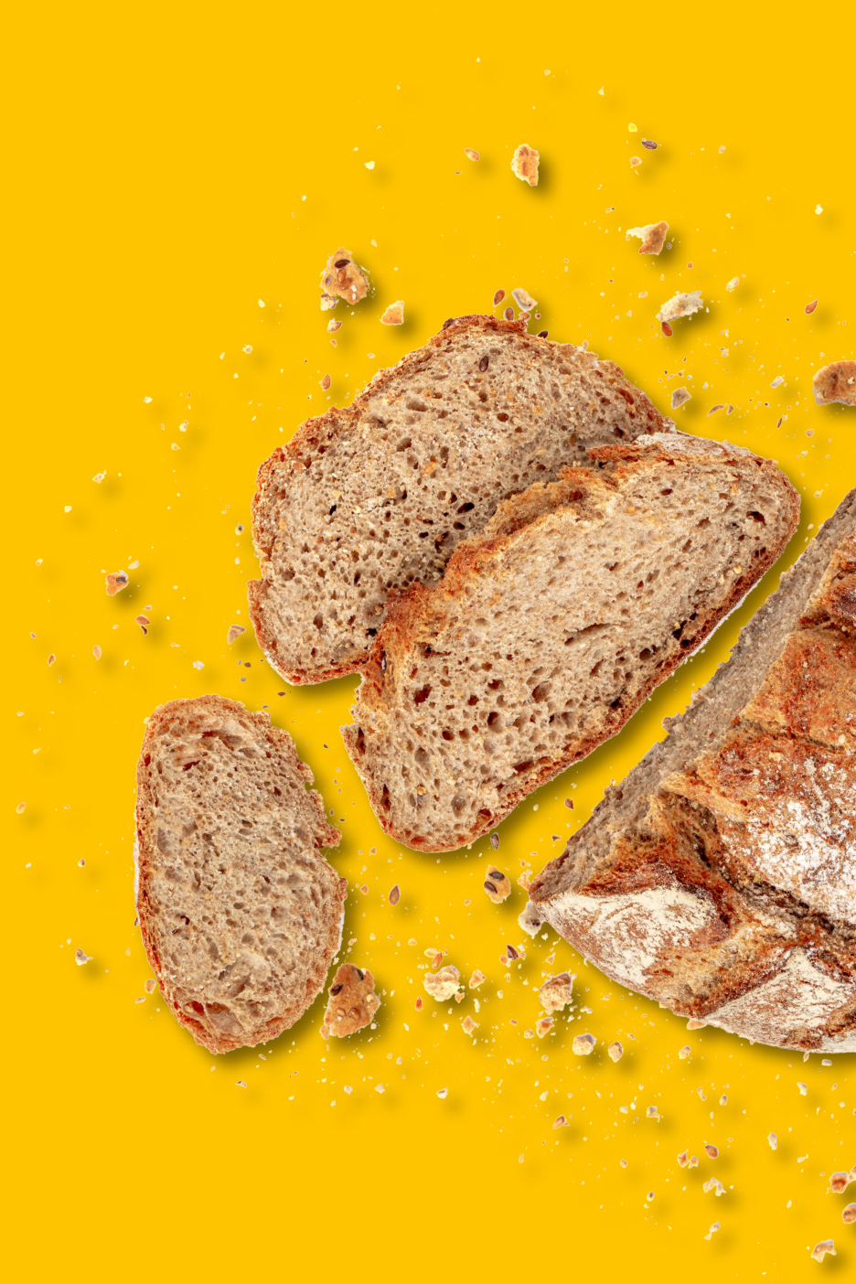 Tranches de pain de seigle et miettes sur fond jaune.