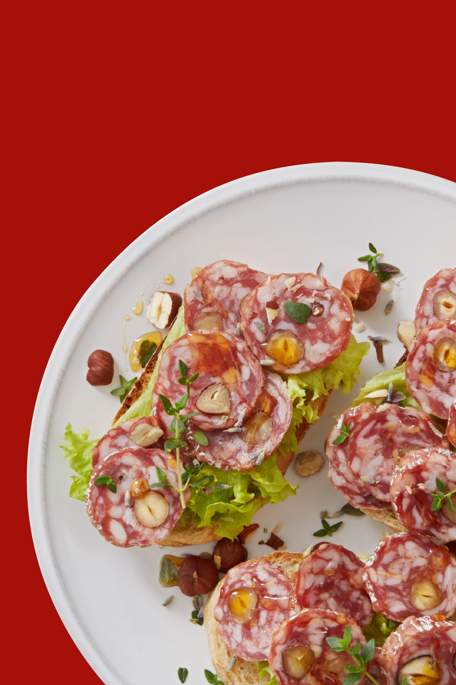 Bruschetta au salami, noisettes, miel et herbes sur une assiette blanche.