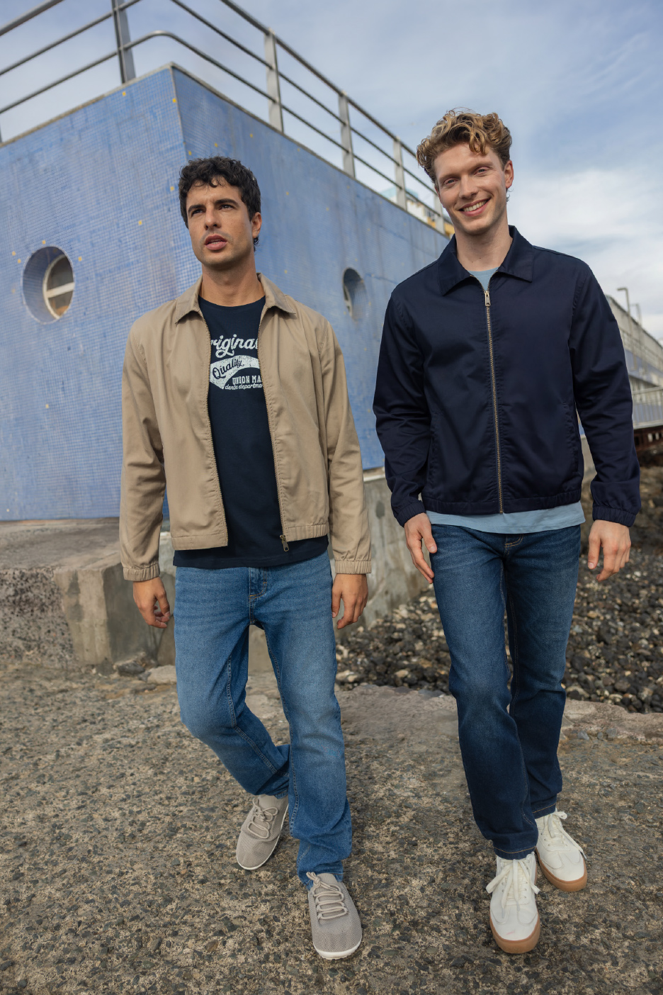 Deux hommes en vestes décontractées, t-shirts et jeans, marchant sur un quai.