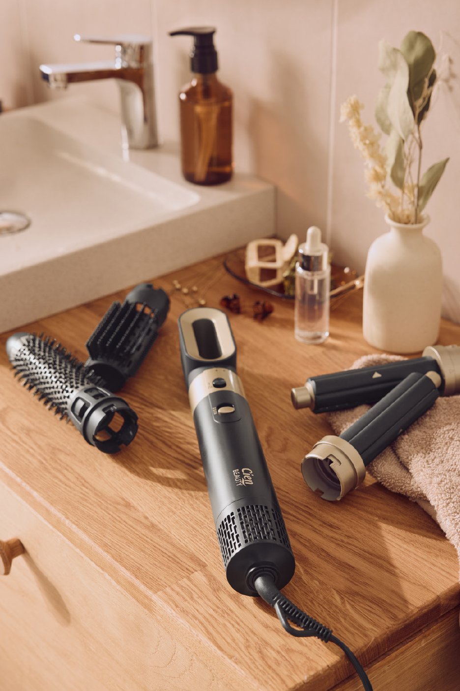 Brosse soufflante multifonctionnelle avec accessoires de coiffage sur un comptoir de salle de bain en bois.