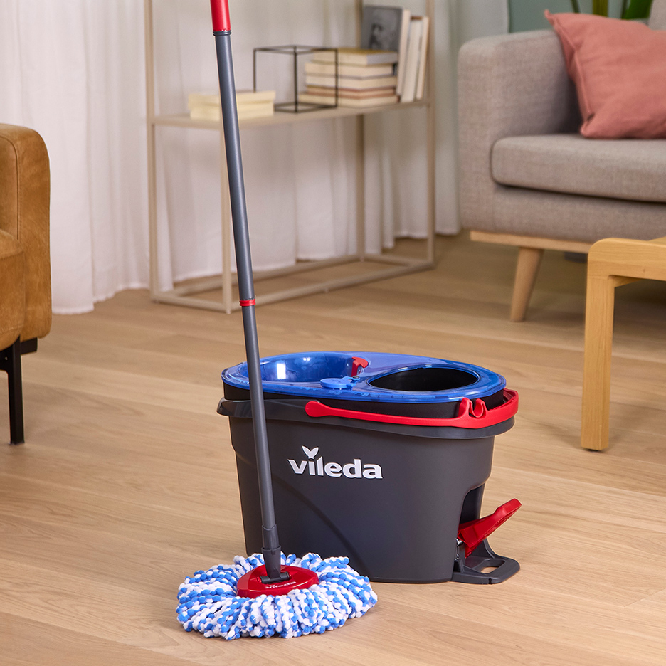 Serpillière Vileda et seau essoreur sur un sol en bois dans un salon.