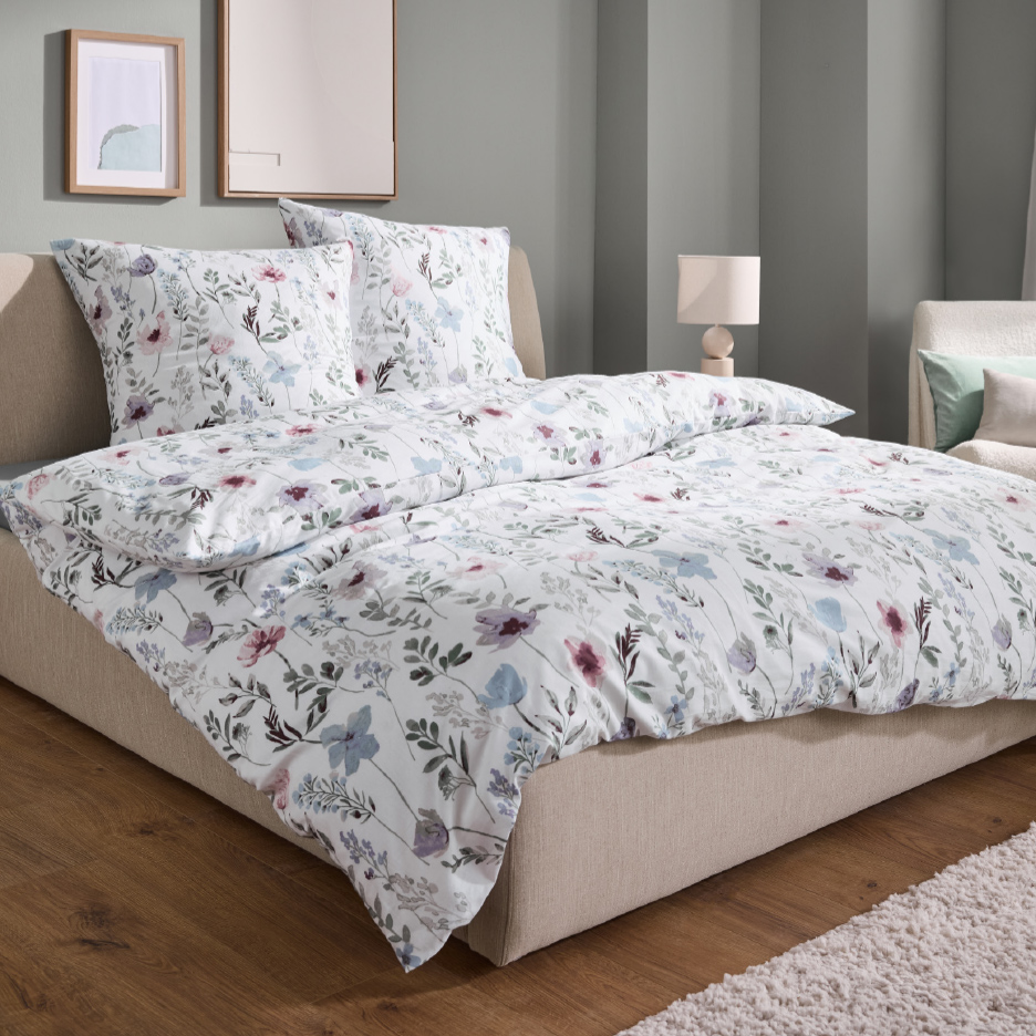 Parure de lit blanche à motifs floraux dans une chambre moderne.