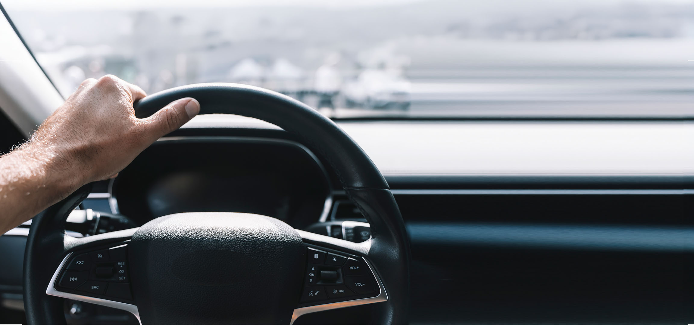 Main d'homme tenant le volant d'une voiture.