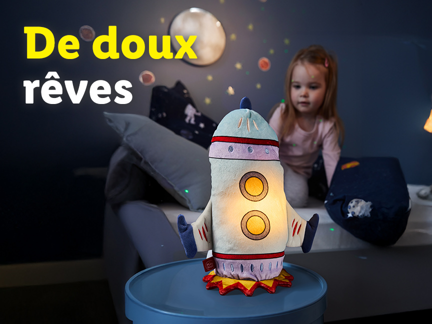 Une veilleuse fusée lumineuse sur une table de chevet avec une petite fille en arrière-plan.