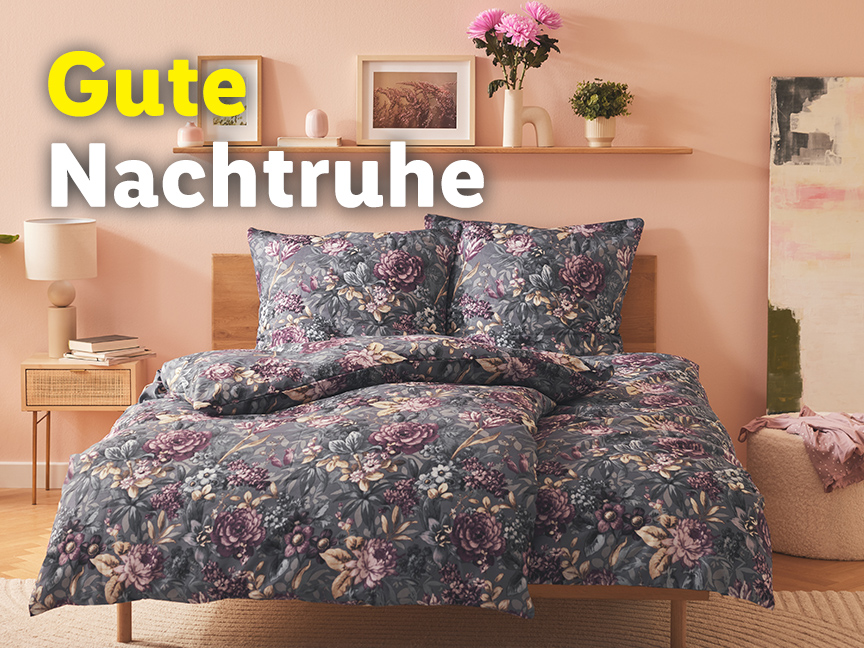 Graue Blumen-Bettwäsche auf einem Bett in einem Schlafzimmer.