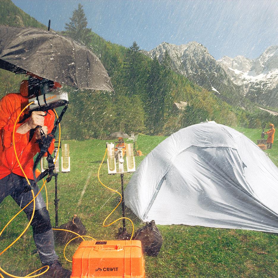 Personne en tenue de pluie testant du matériel de camping sous la pluie avec des montagnes.