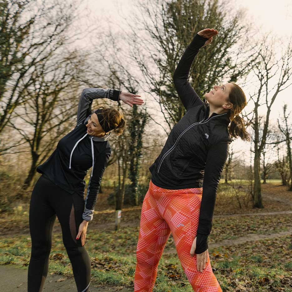 Deux femmes en tenue de sport s'étirent en plein air.