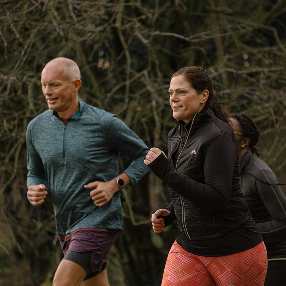 Deux coureurs adultes en tenue de sport faisant du jogging en extérieur.