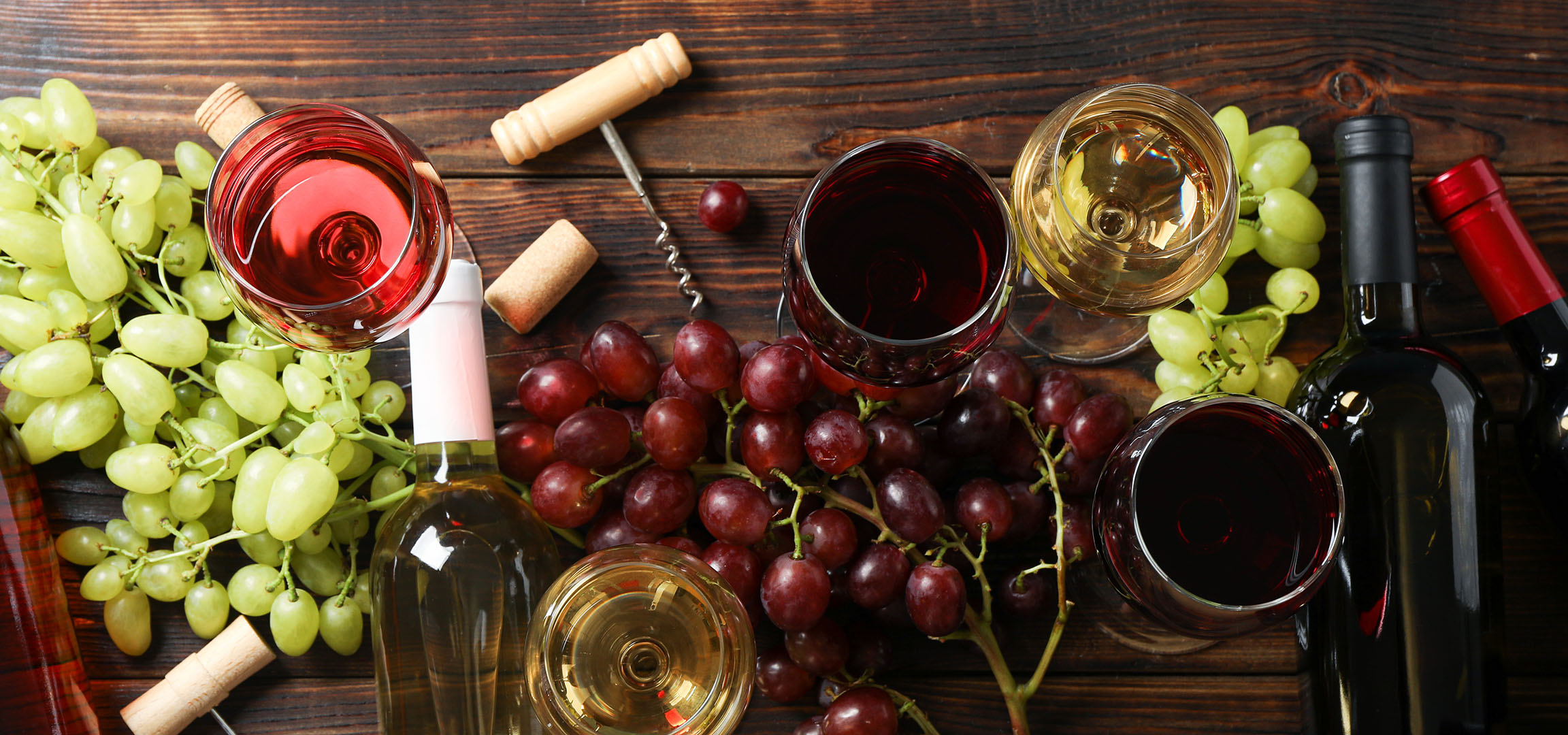 Divers vins, raisins et accessoires de vin sur une table en bois.