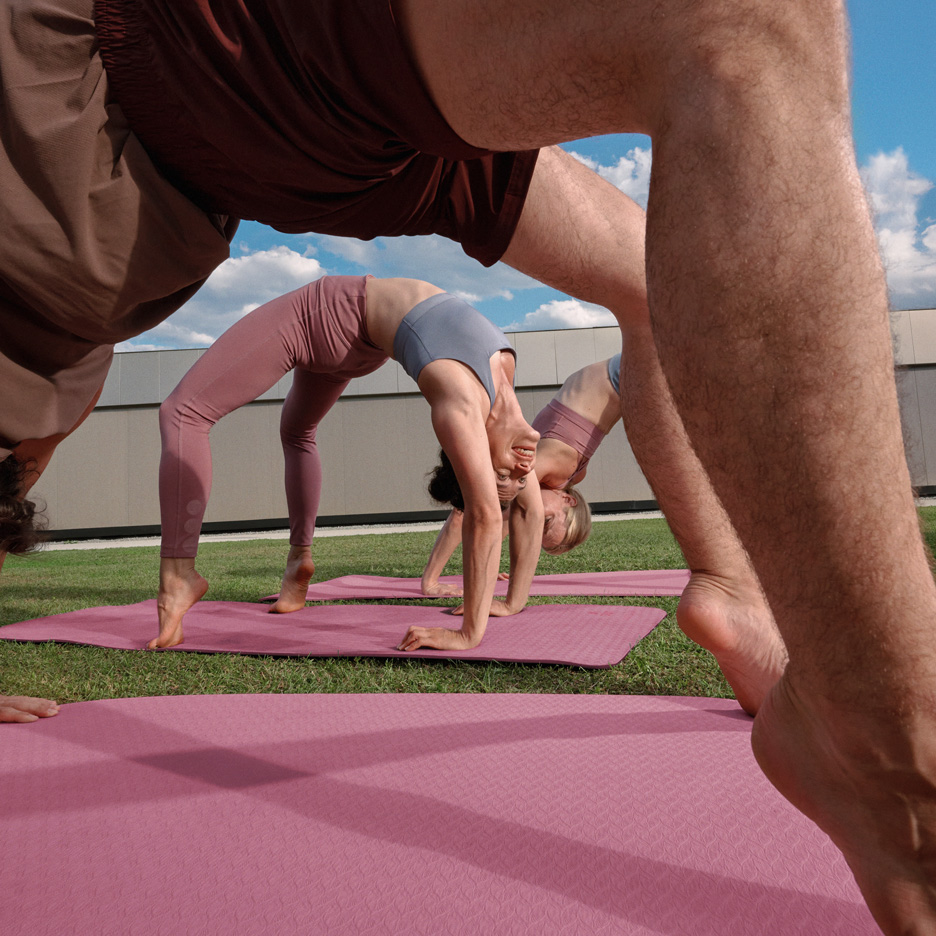 Personnes faisant du yoga en extérieur sur des tapis de yoga, en tenue de sport.