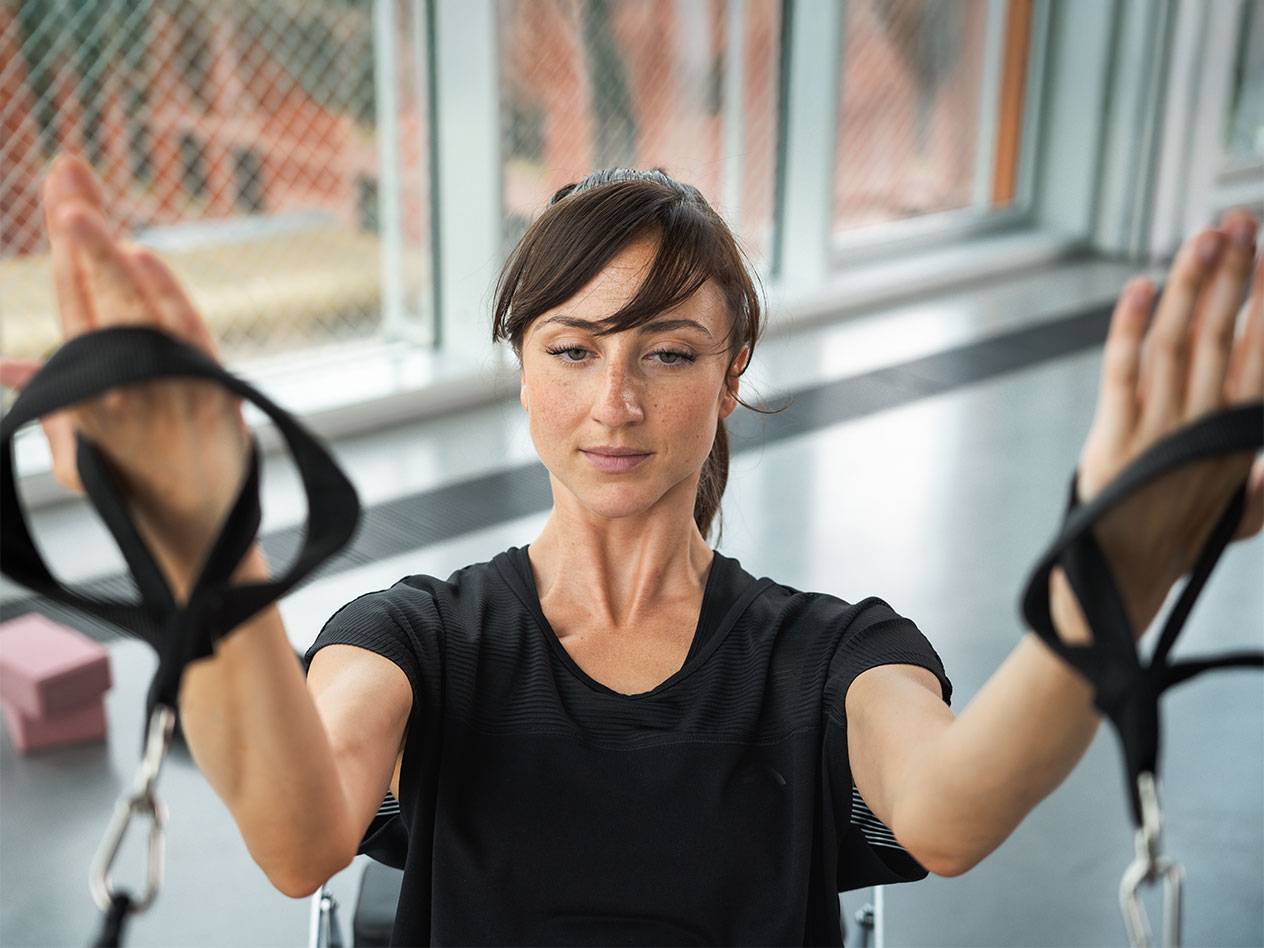 Femme s'entraînant avec des bandes de résistance dans une salle de sport.