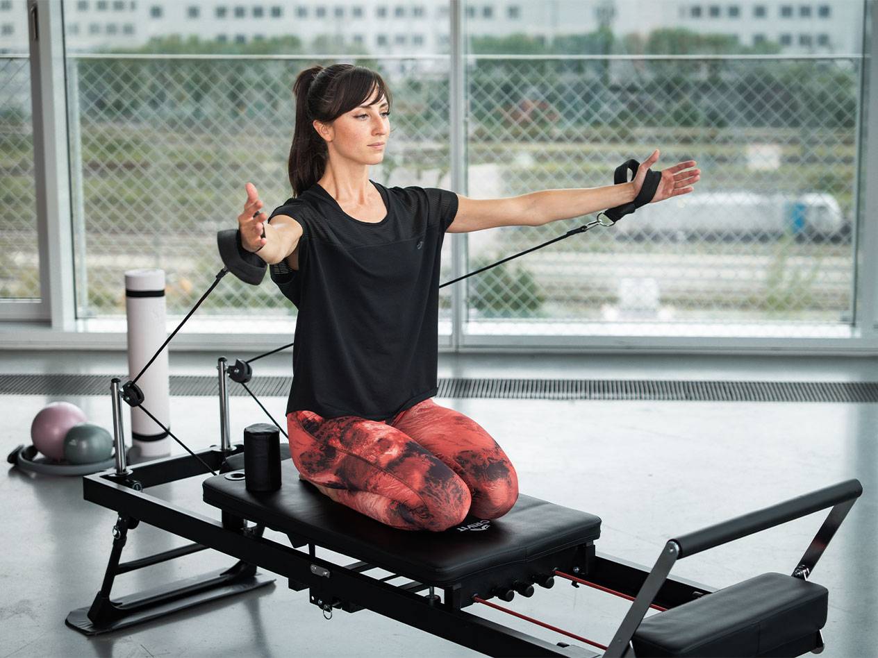 Femme faisant du Pilates sur un reformer avec des bandes de résistance.