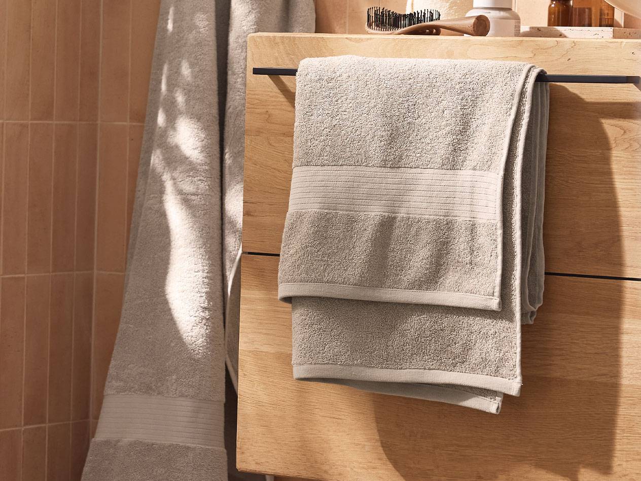 Serviettes gris clair suspendues à une armoire en bois dans une salle de bain.
