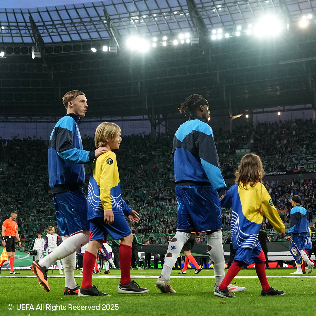 Joueurs de football et enfants marchant sur le terrain d'un stade plein.
