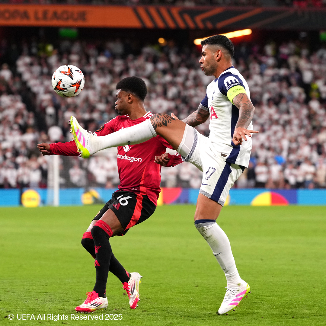 Deux footballeurs en équipement Adidas et Nike se disputent le ballon sur le terrain.