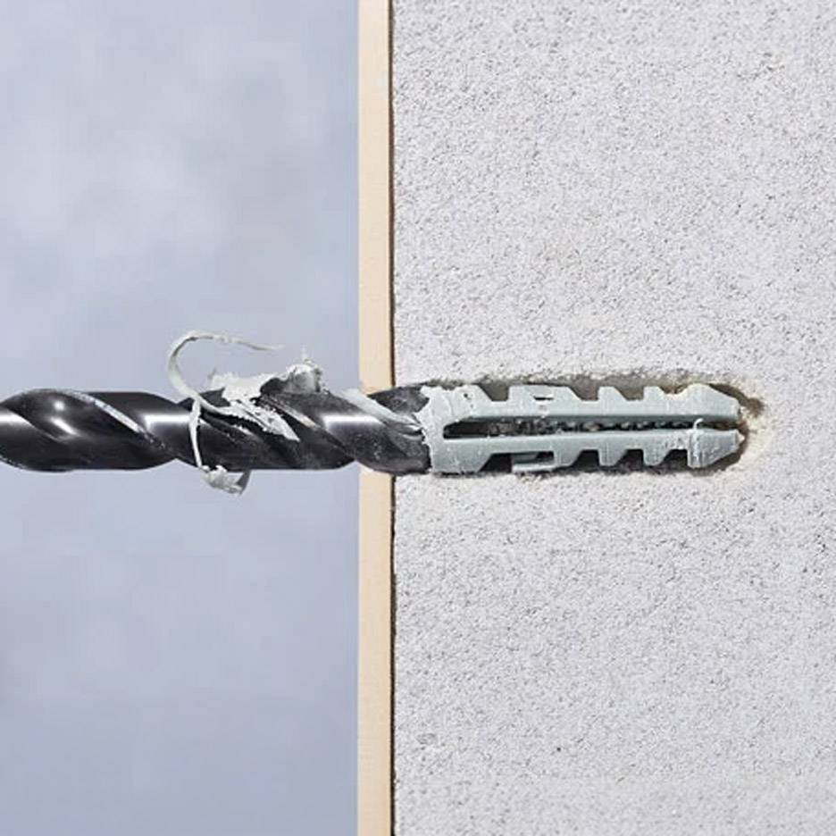 Foret perçant un mur avec une cheville de fixation.