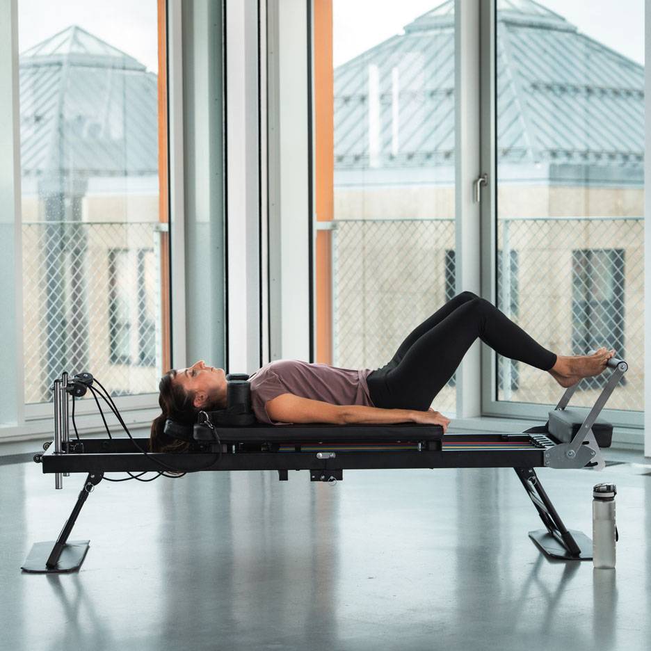 Femme faisant des exercices de Pilates sur une machine reformer.