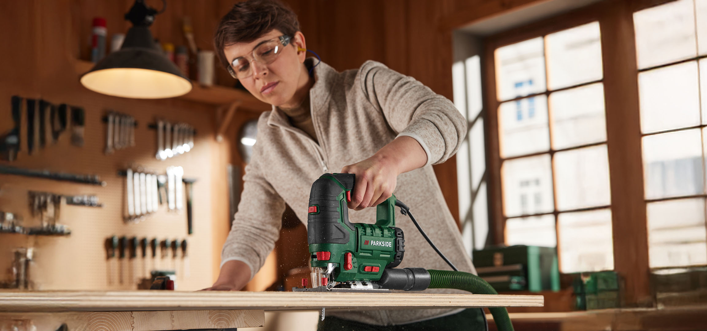 Une femme utilise une scie sauteuse Parkside pour couper du bois.