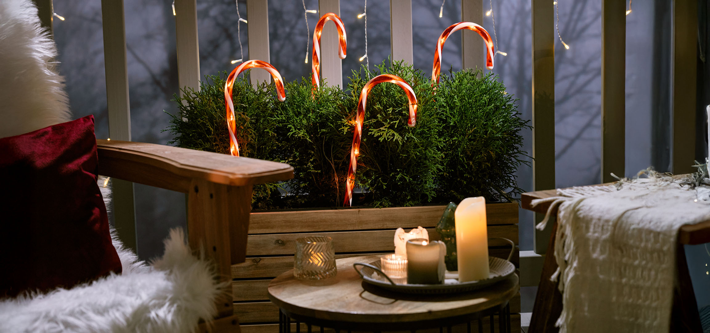 Balcon décoré pour Noël avec une chaise, des bougies et des cannes de bonbon.