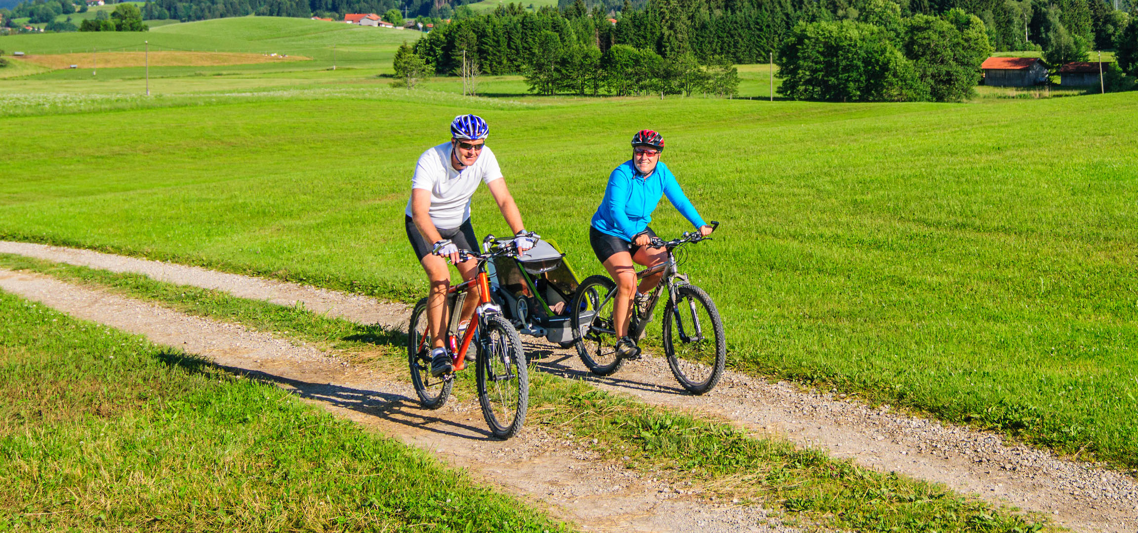 Couple à vélo dans un paysage vert.