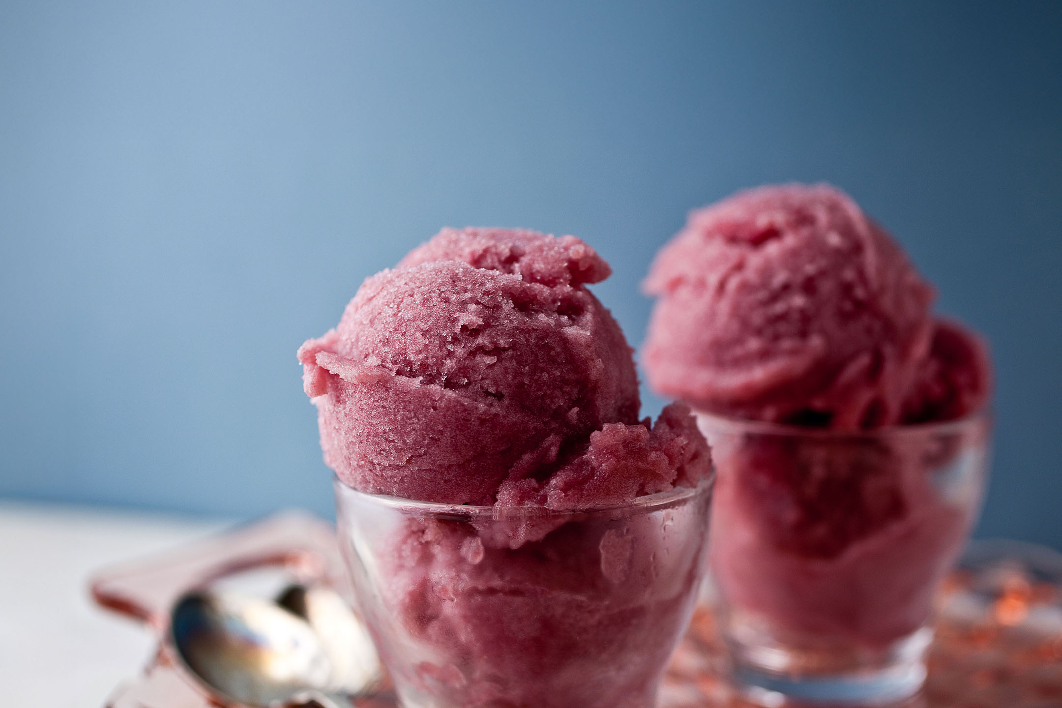 Deux verres de sorbet ou de glace rose sur une table blanche avec un fond bleu.