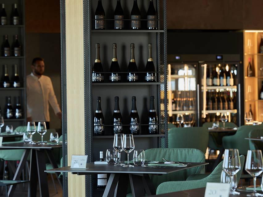Intérieur de restaurant avec des bouteilles de vin sur des étagères et des tables dressées.