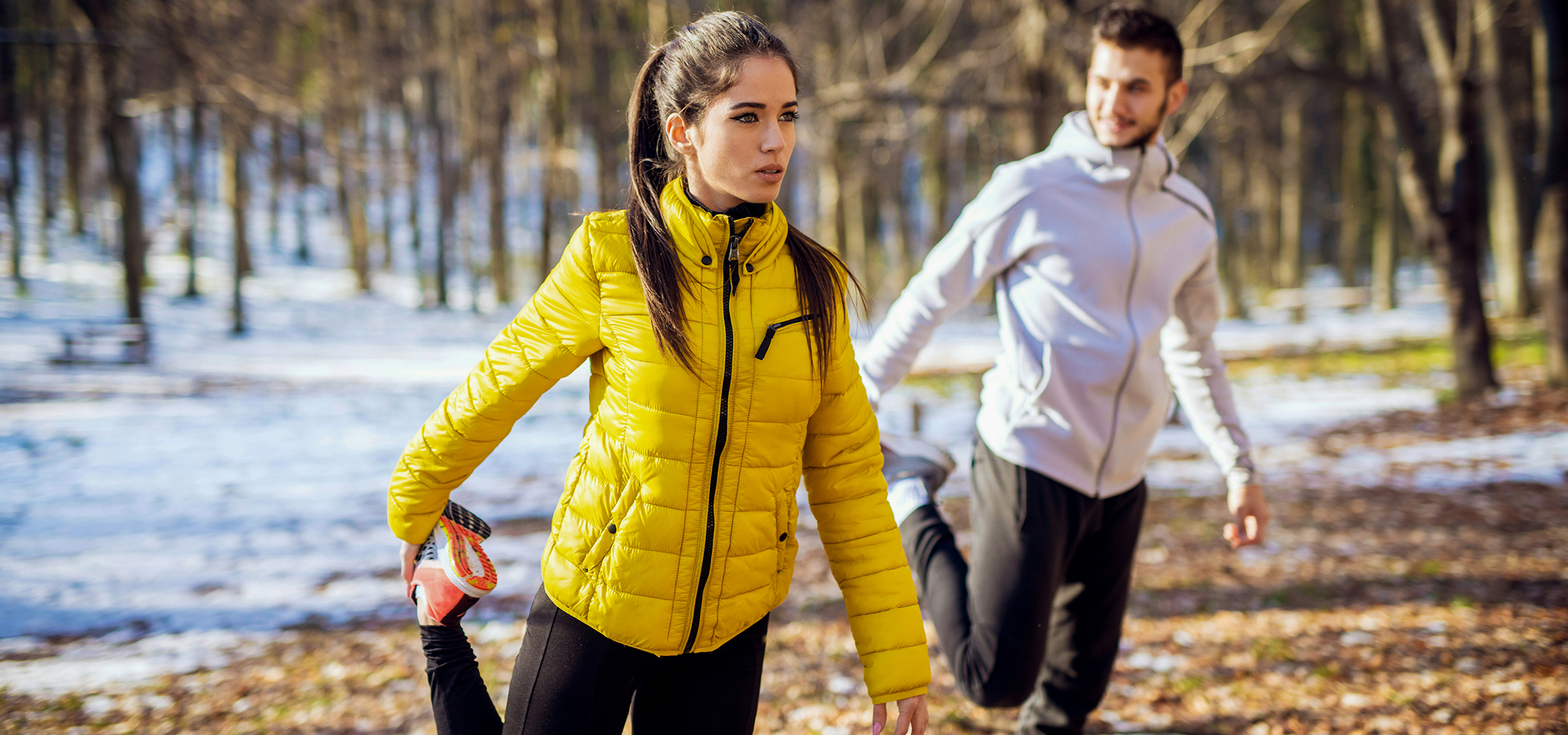 Deux personnes en tenue de sport d'hiver, une femme en veste jaune et un homme en veste blanche.
