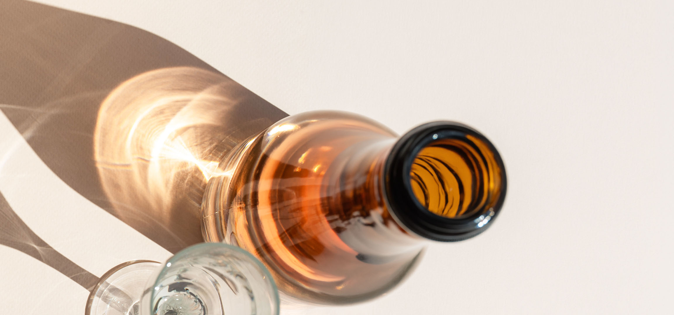 Verres et bouteille avec des ombres et des reflets de lumière sur un fond clair
