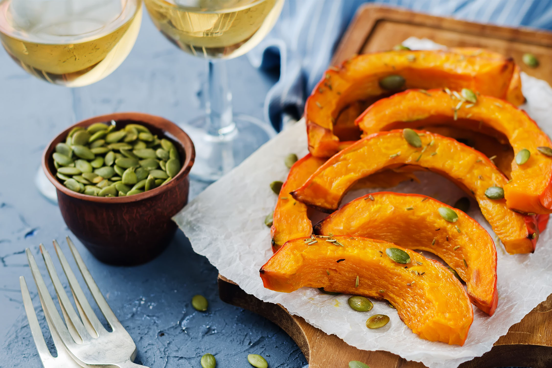 Quartiers de potiron rôtis avec graines de courge et romarin, servis avec du vin blanc.