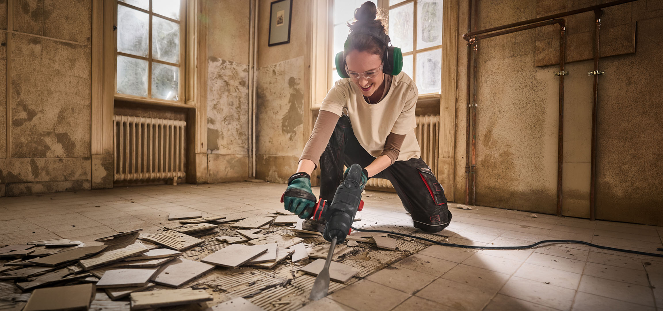 Femme utilisant un marteau-piqueur pour enlever le carrelage dans une vieille pièce