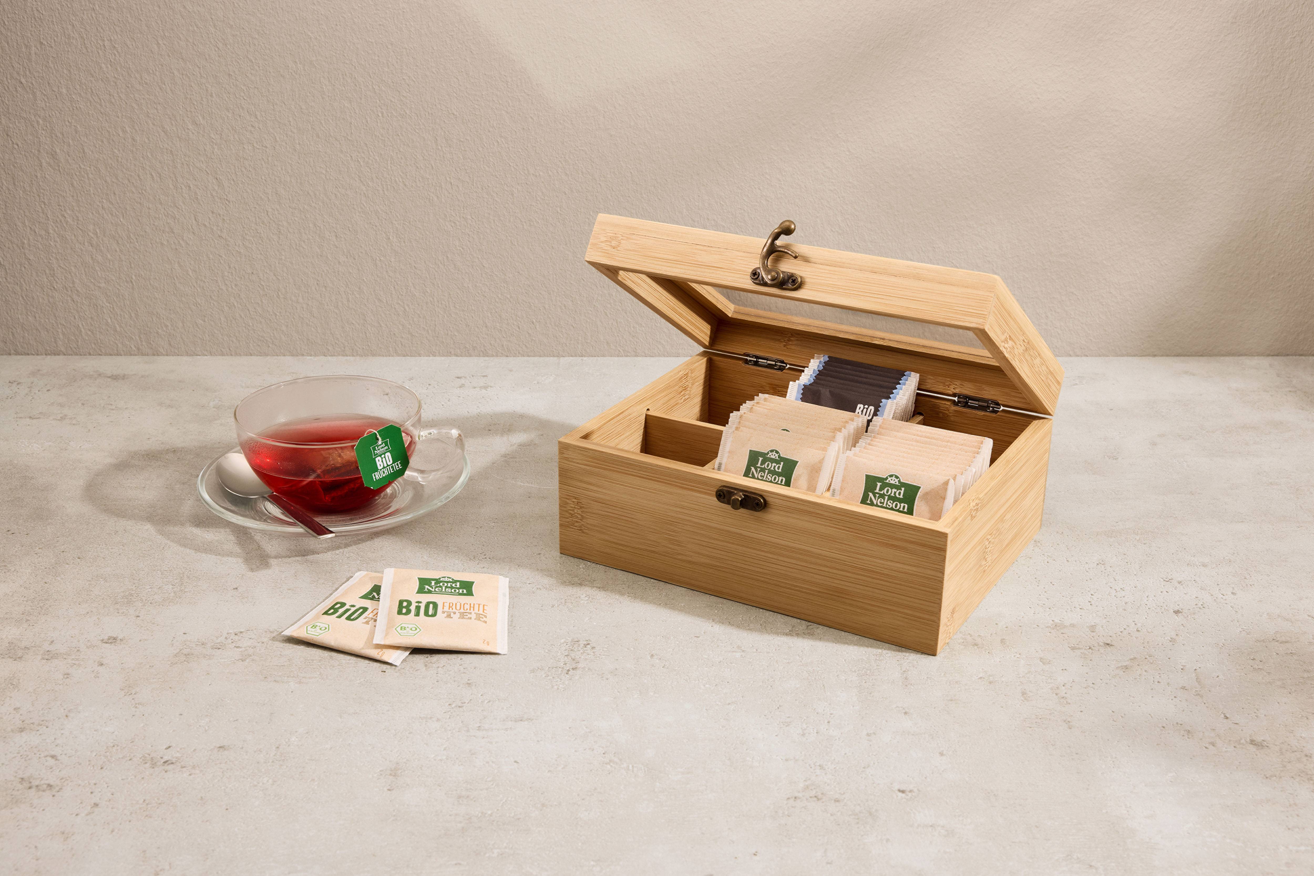 Tasse à thé en verre et boîte à thé en bois avec sachets de thé.