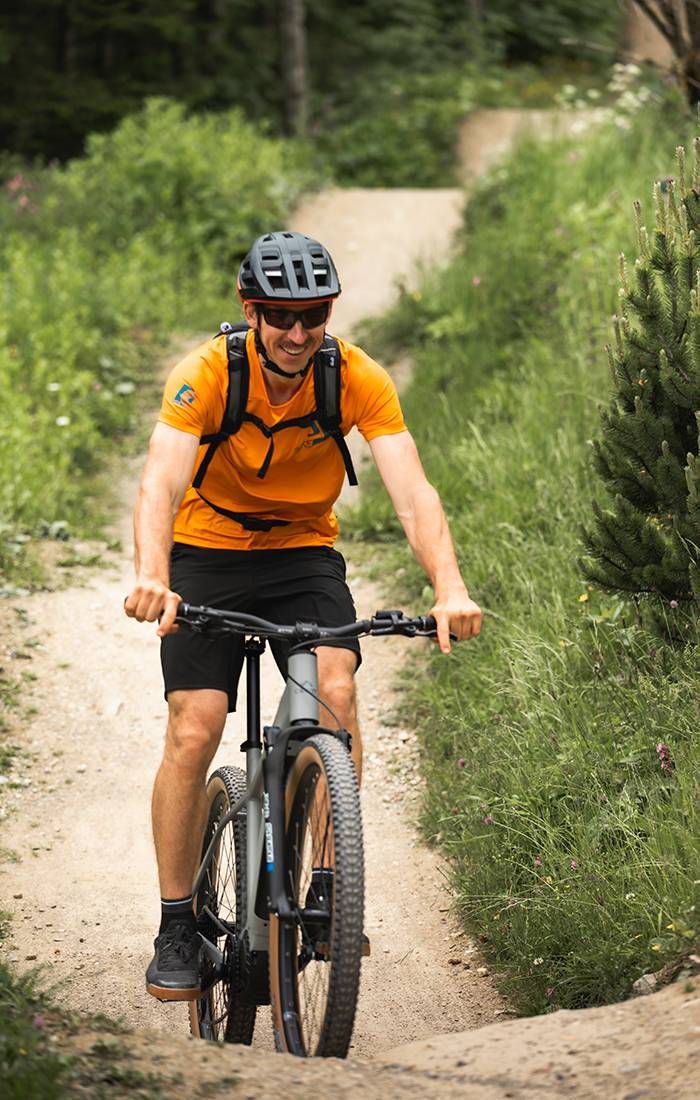 Un homme sourit en faisant du VTT sur un sentier.